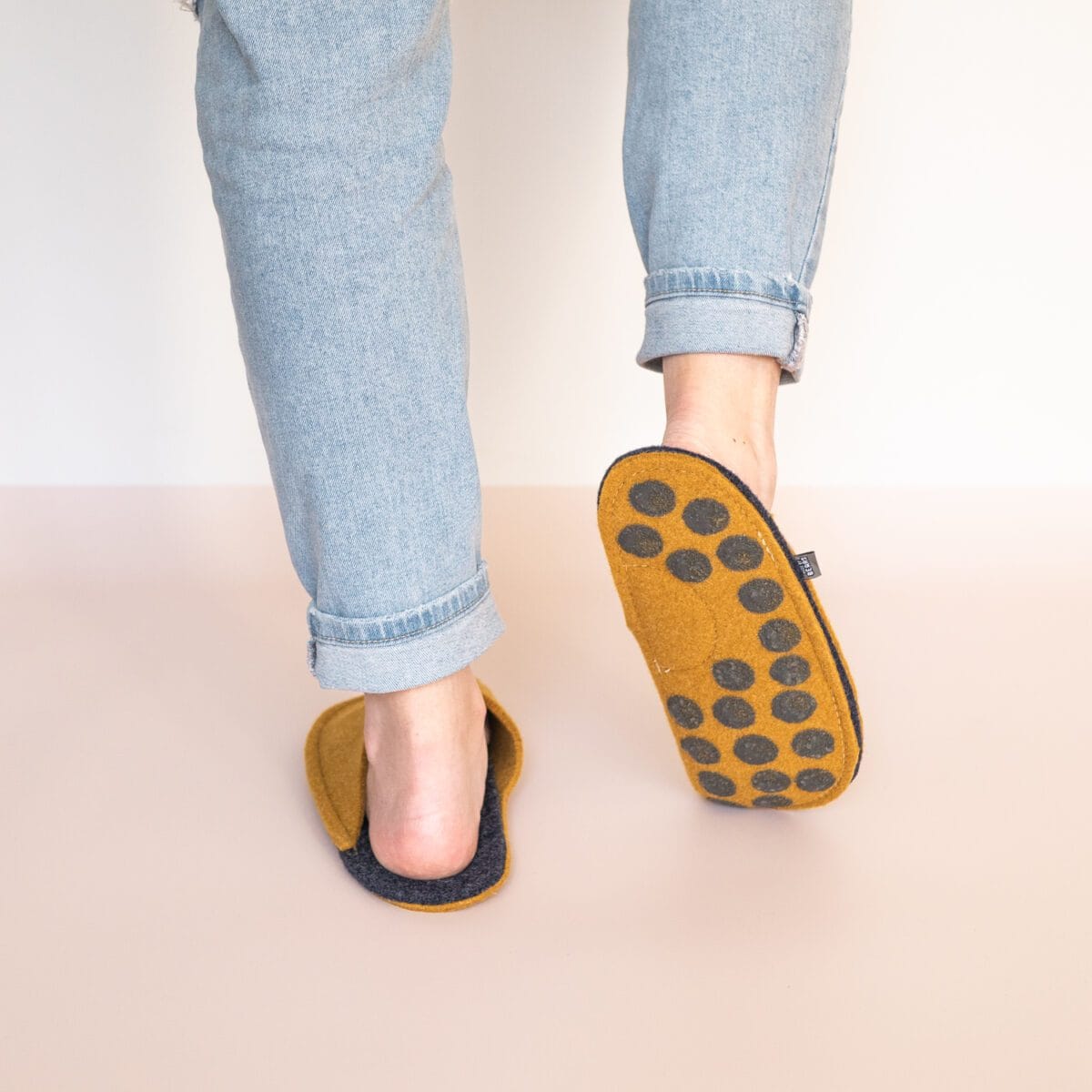 A woman wearing curcuma yellow and navy blue slippers