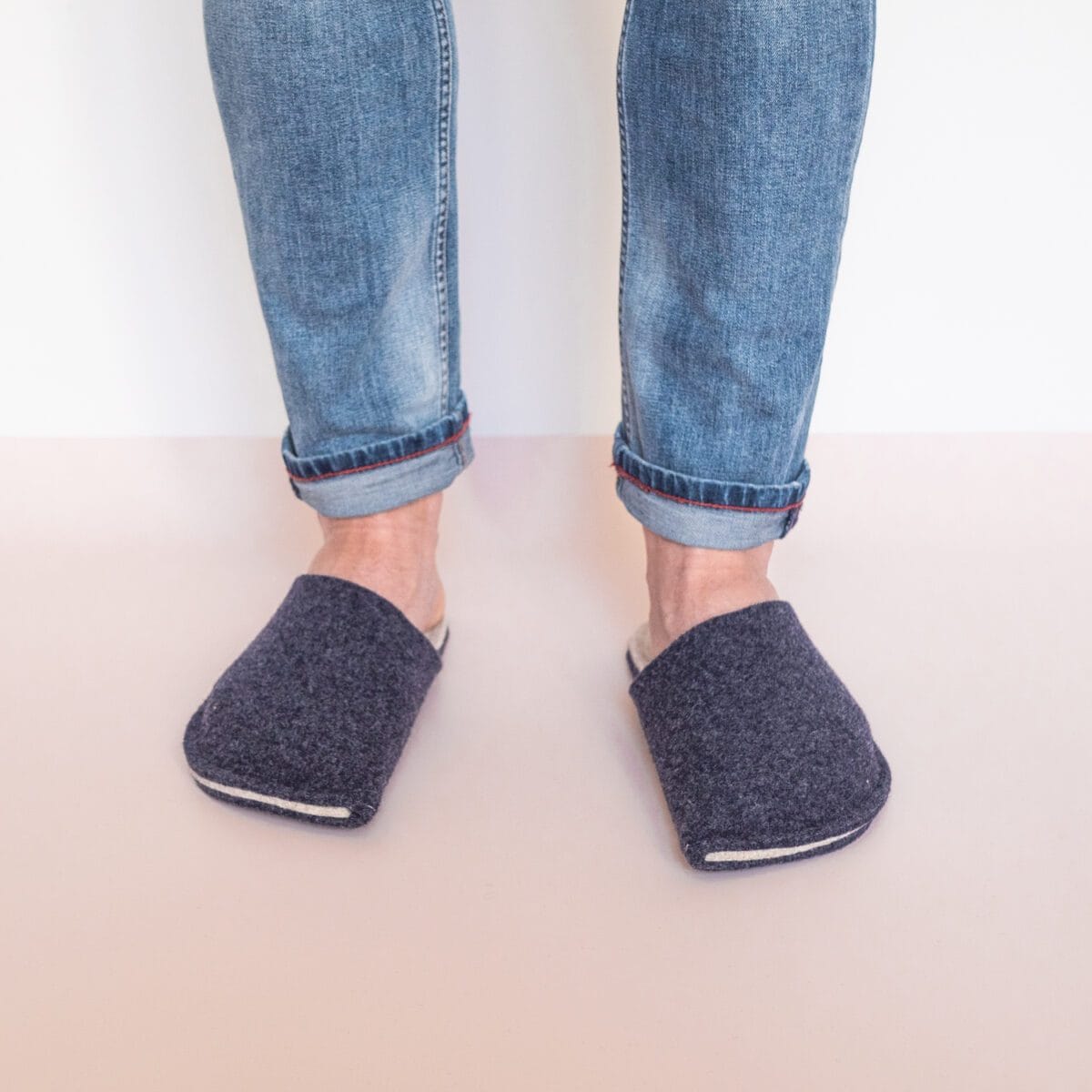 A man standing wearing navy blue and cream white slippers