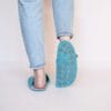 A woman wearing handmade house slippers made of turquoise blue and light gray wool felt slippers