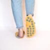 A woman wearing house slippers made of peach yellow and light gray wool felt
