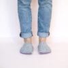 A man wearing house slippers made of light gray and purple wool felt